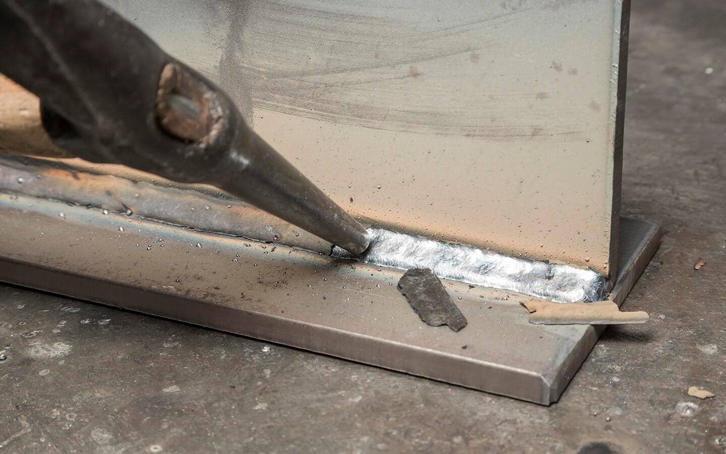 Slag being chipped away from a weld with a welding hammer.