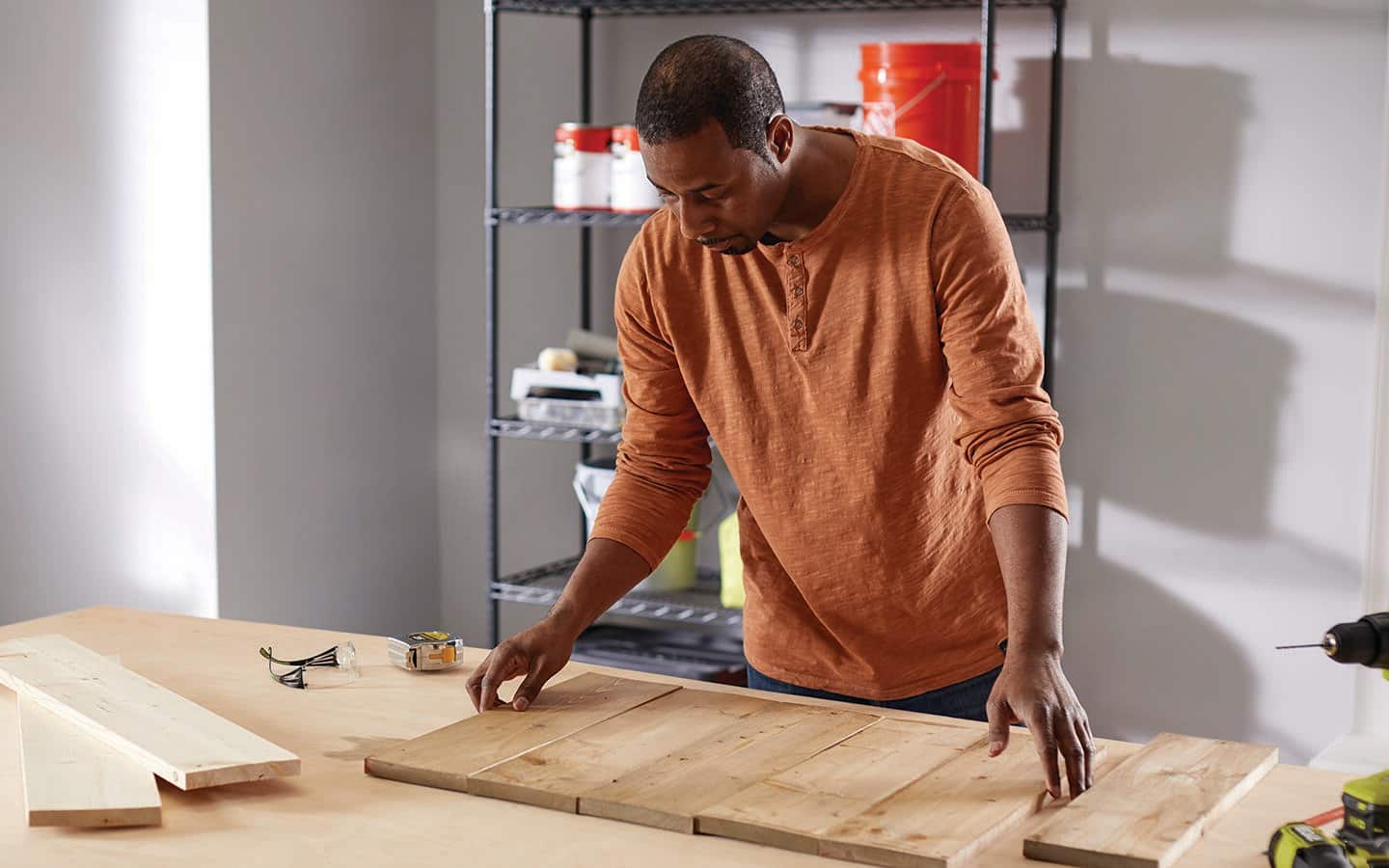 A man preparing wooden planks to assemble a Christmas board.