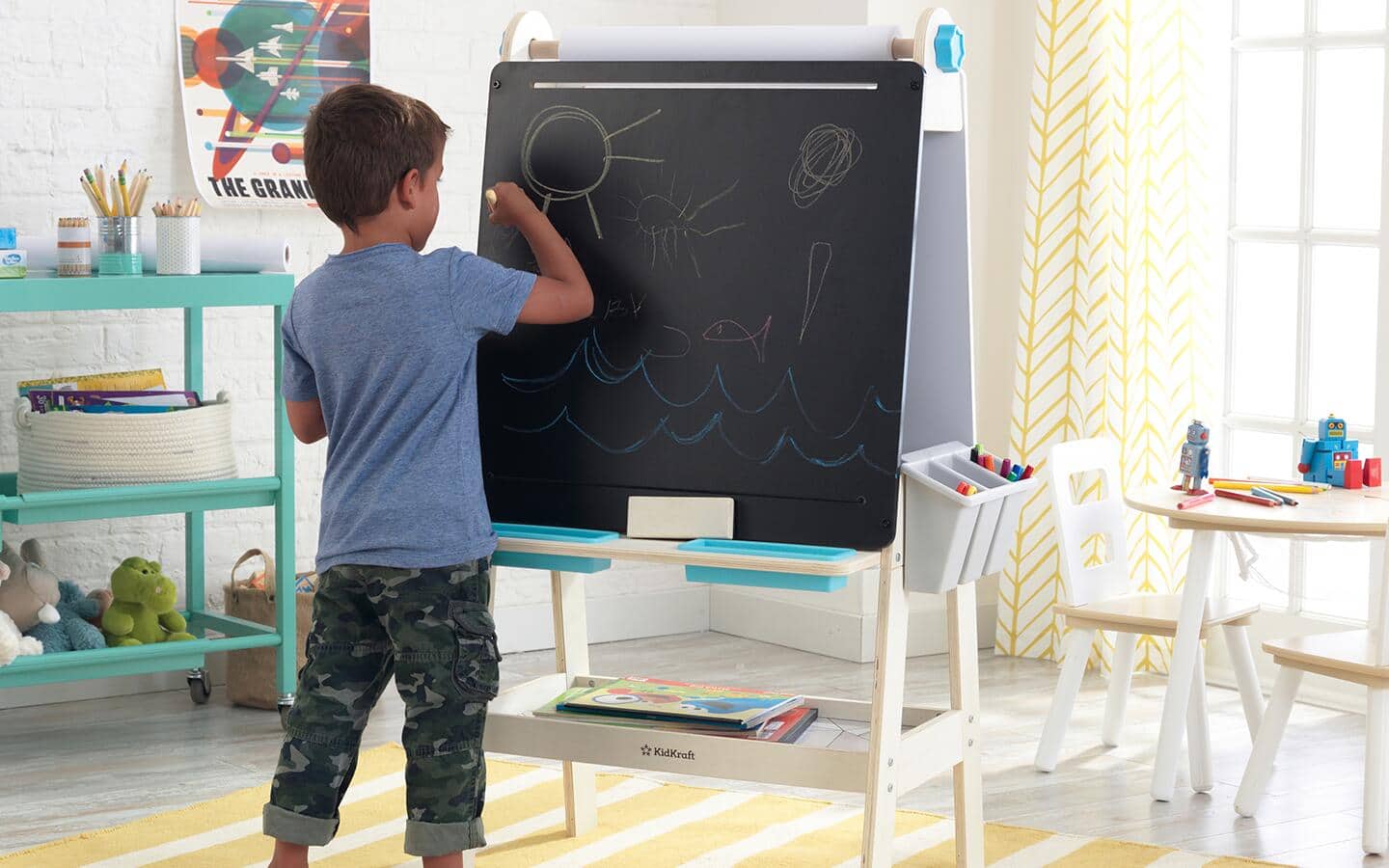 A kid in a playroom draws with chalk on an easel. A kid in a playroom draws with chalk on an easel.