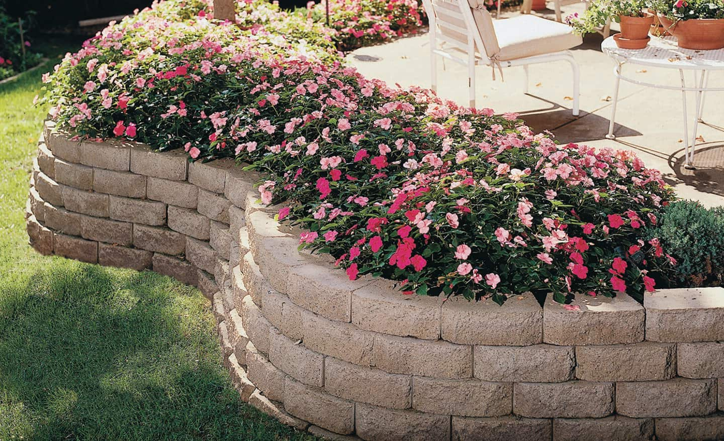 A stone retaining wall with a flower bed in a backyard