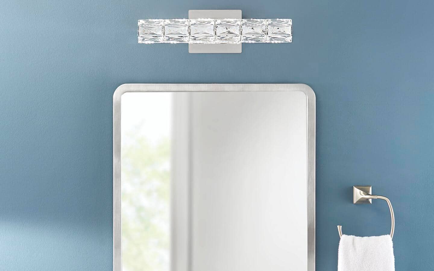 White vanity bar light with bright metal finishes installed over a glam mirror. White vanity bar light with bright metal finishes installed over a glam mirror.