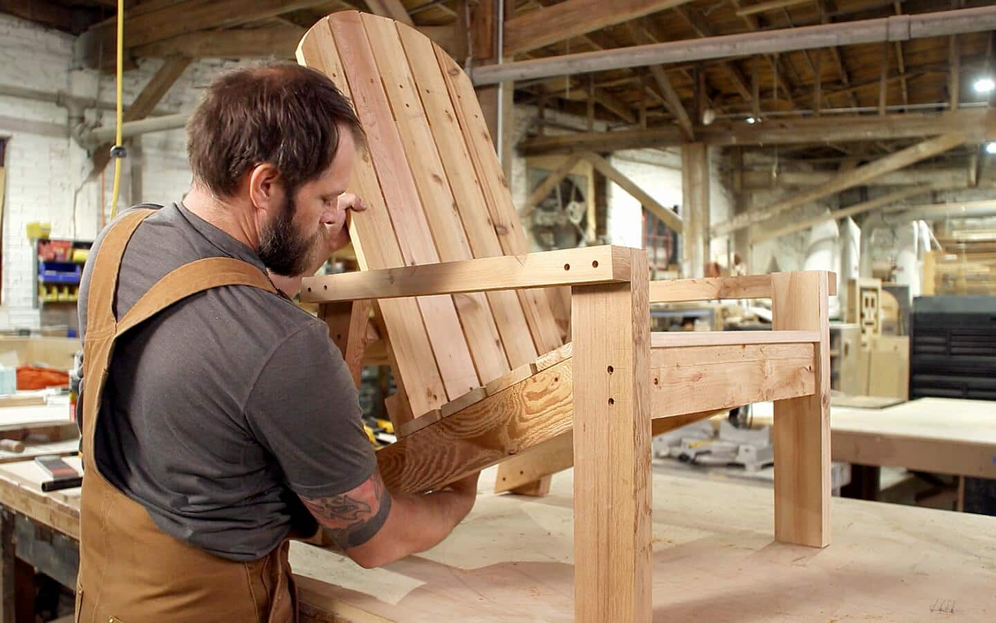 A person attaching the back of an Adirondack chair. A person attaching the back of an Adirondack chair.