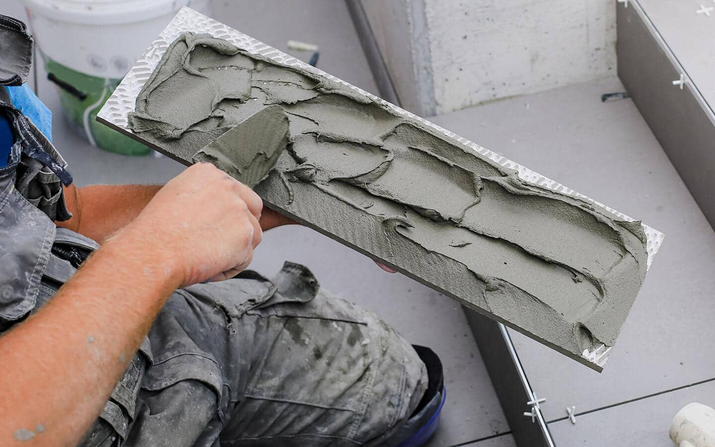 A person uses a trowel to apply concrete repair material to steps. A person uses a trowel to apply concrete repair material to steps.