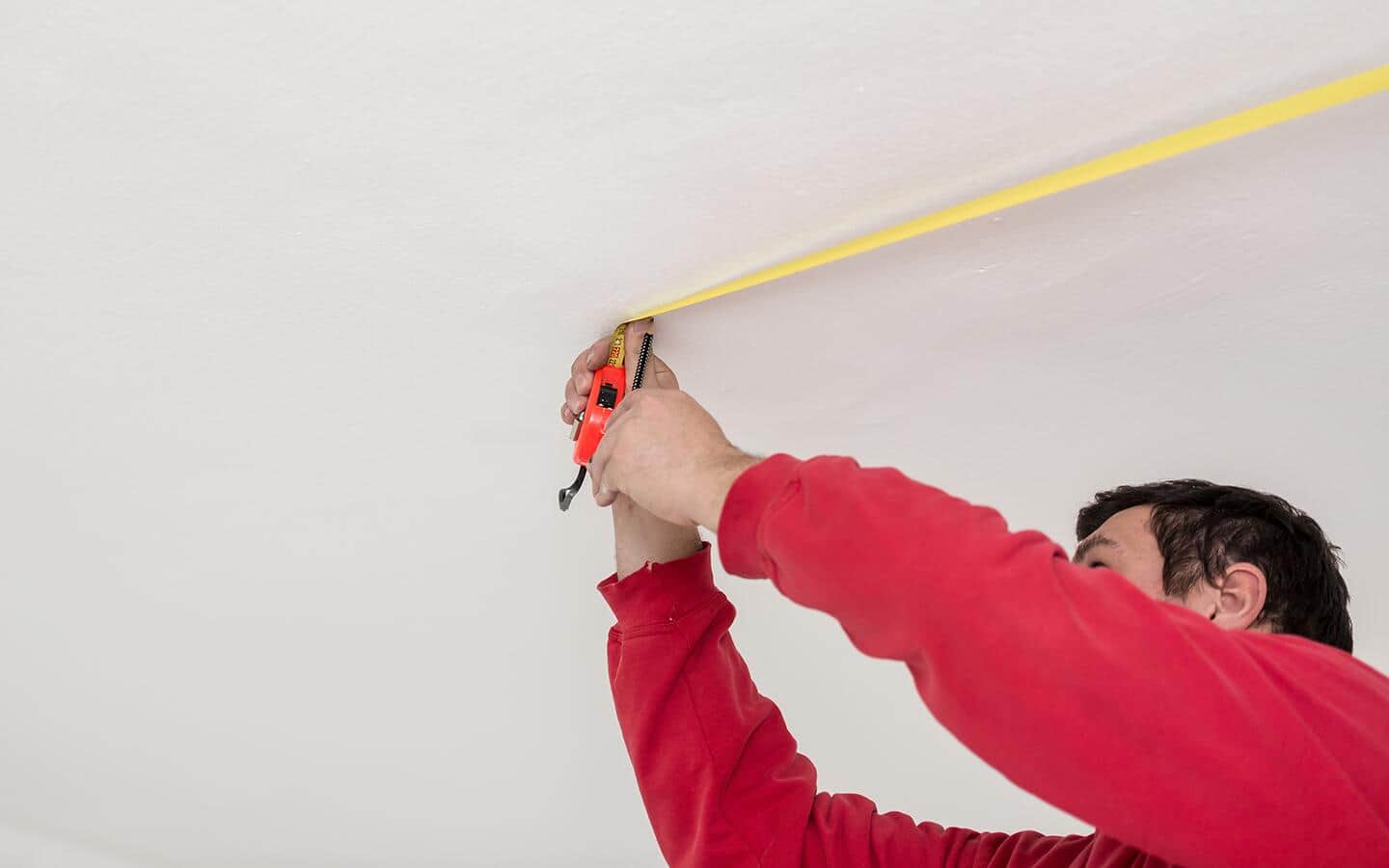 A person measures a ceiling. A person measures a ceiling.
