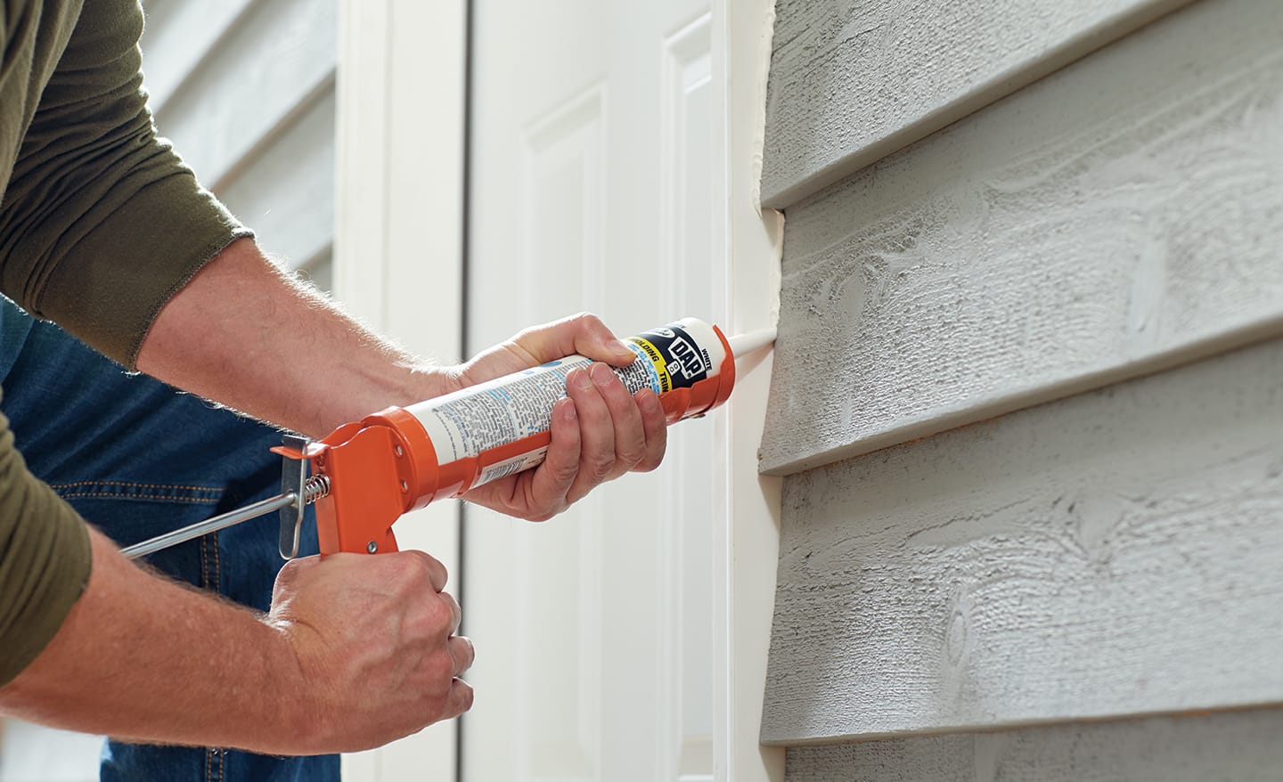 A man caulking the exterior of a new entry door.