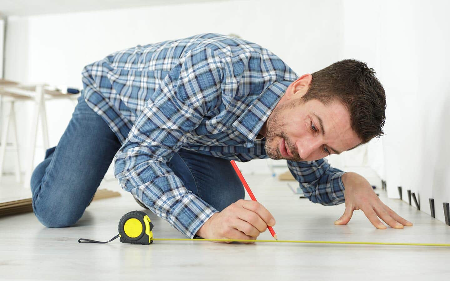 A person measures the size of a room with a tape measure. A person measures the size of a room with a tape measure.