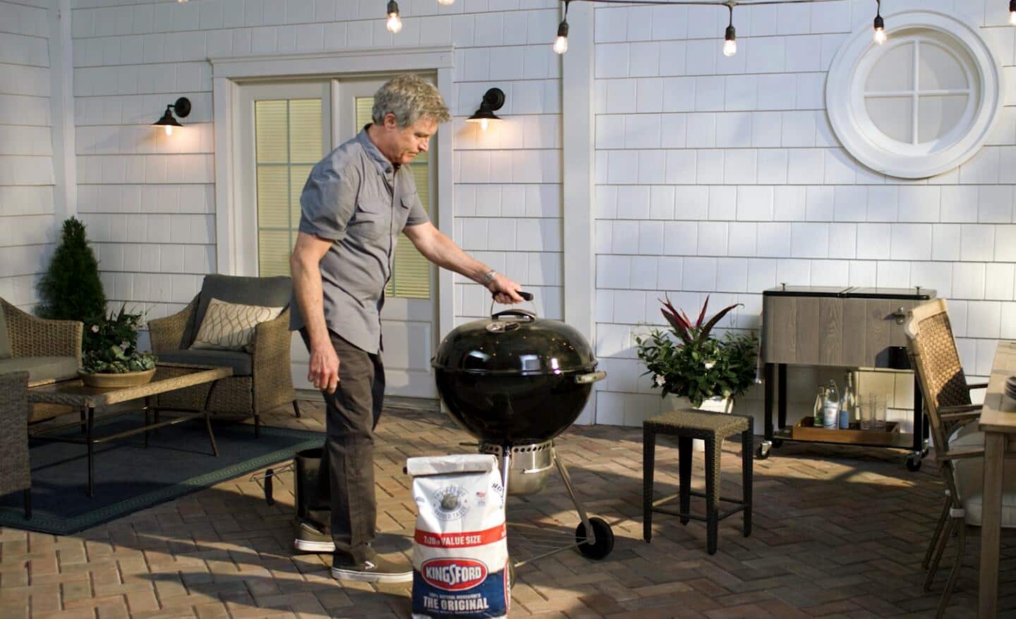 Man standing in front of a charcoal grill.