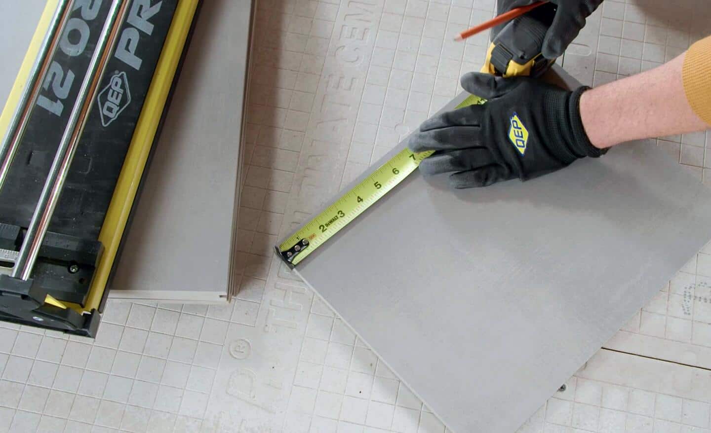 A person measures and scores tile for cutting.