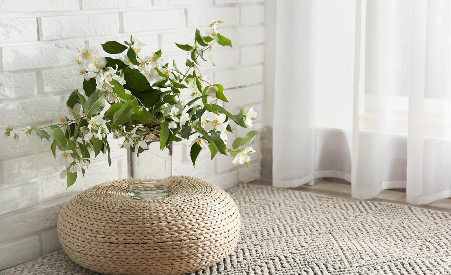 A large jasmine vine growing in glass on a beige basket.