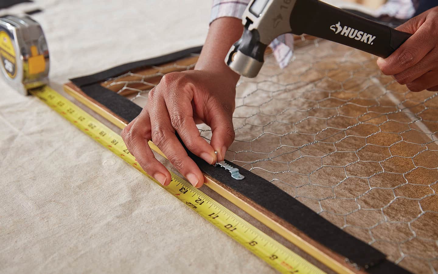 A person hammers a hanger on a frame. A person hammers a hanger on a frame.