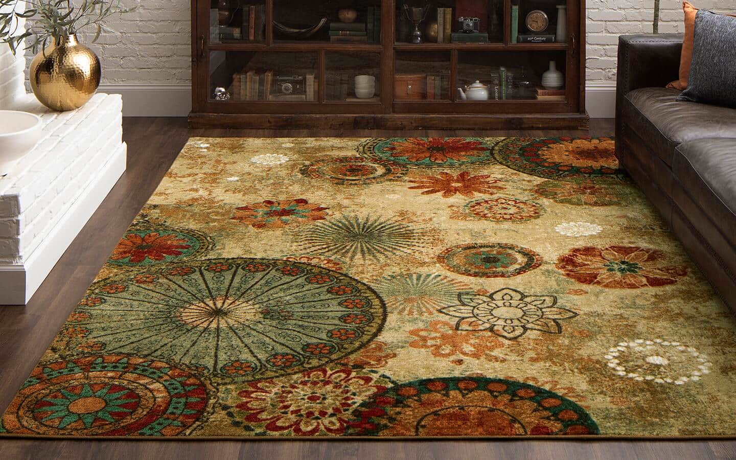 A medallion rug lays on a living room floor between a fireplace and a sofa.
