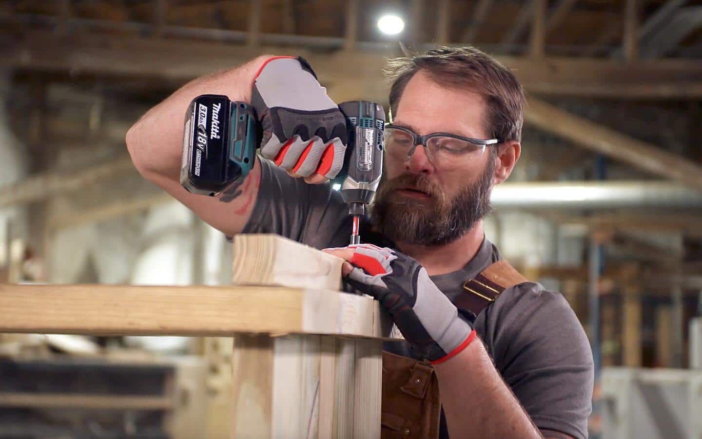 A person screwing wood feet into an outdoor grill station's baseboard.