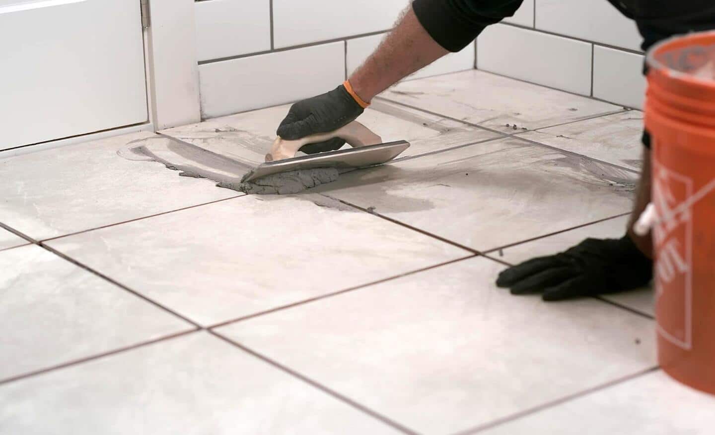 Person applying grout to a tile floor