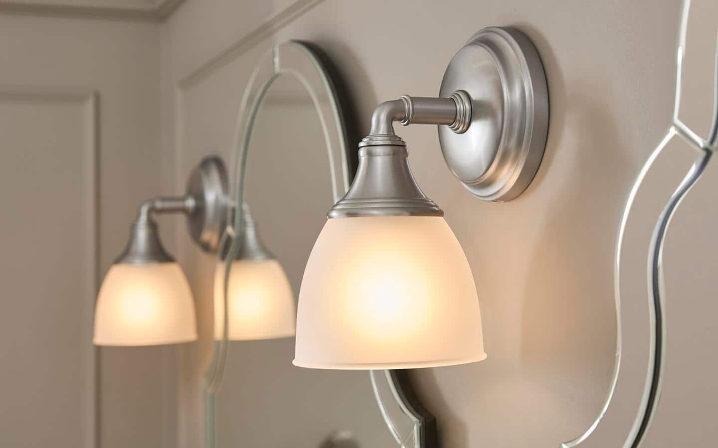 Two brushed-nickel wall sconces installed on a wall with mirrors. Two brushed-nickel wall sconces installed on a wall with mirrors.