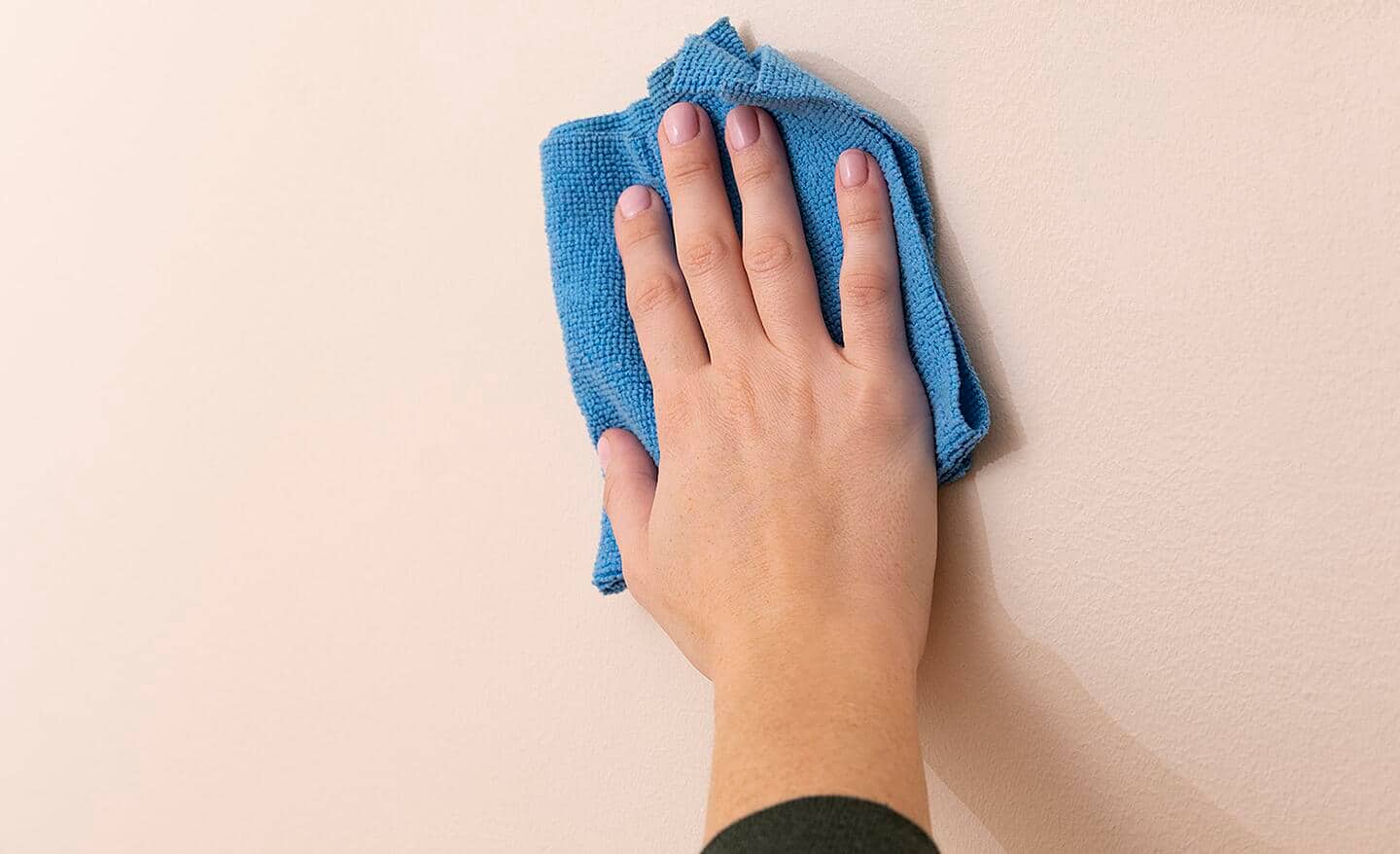 A person wiping down a wall with a cloth.