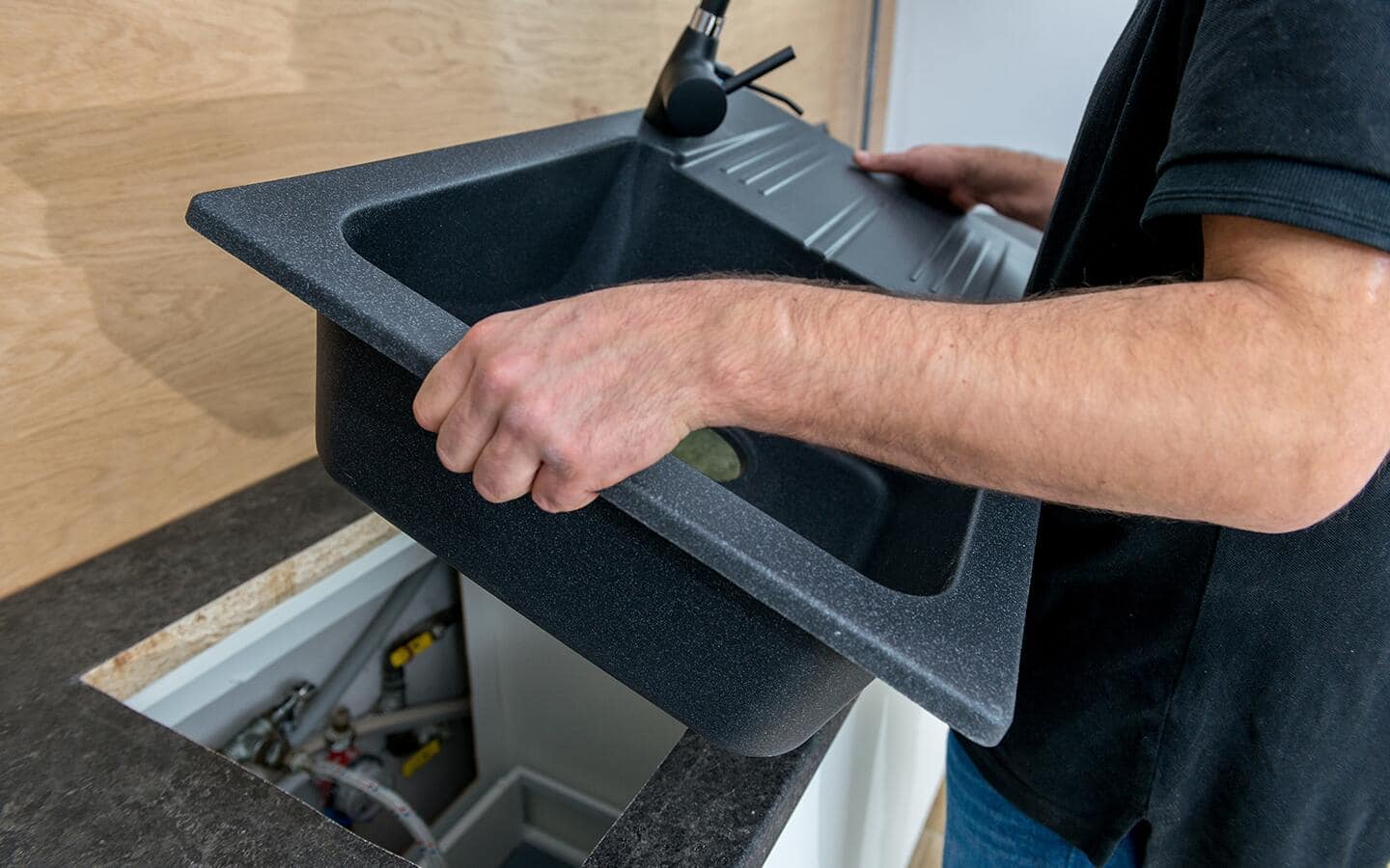 An individual removing an old kitchen sink from the countertop. An individual removing an old kitchen sink from the countertop.
