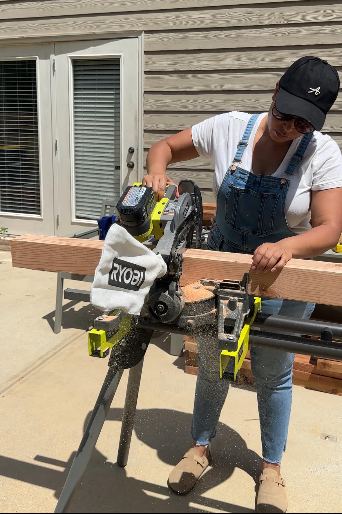 A woman using a RYOBI circular saw to cut a piece of lumber. A woman using a RYOBI circular saw to cut a piece of lumber.
