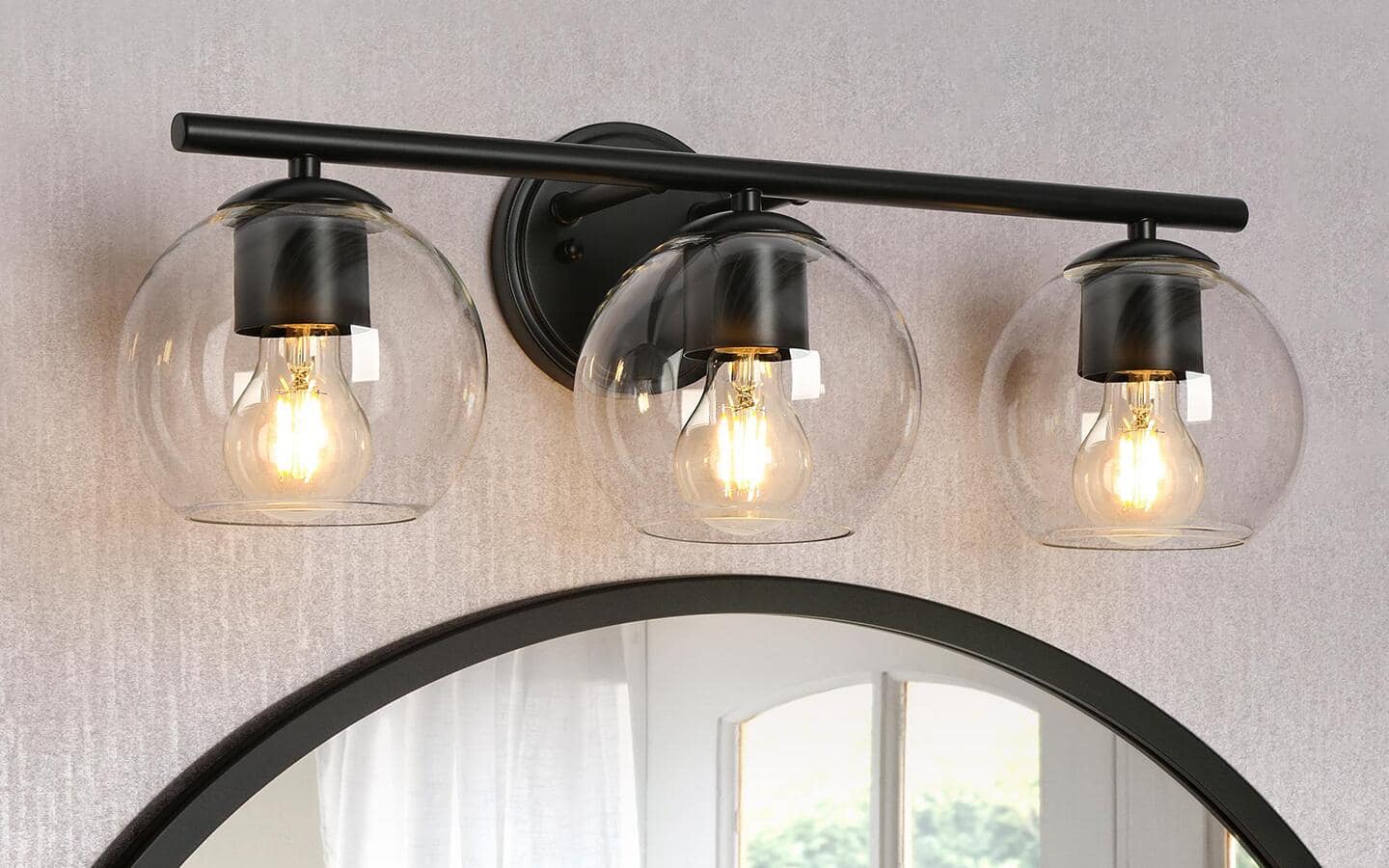 Three vanity lights in a transitional style in a bathroom. Three vanity lights in a transitional style in a bathroom.