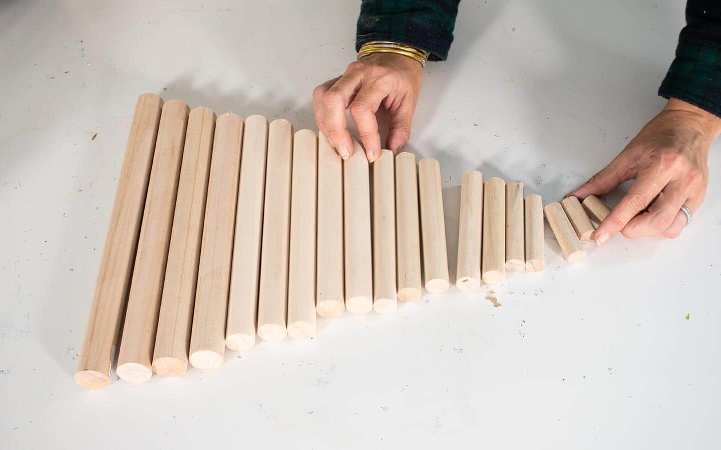 Someone lining up cut pieces of a wood dowel from largest to smallest. Someone lining up cut pieces of a wood dowel from largest to smallest.