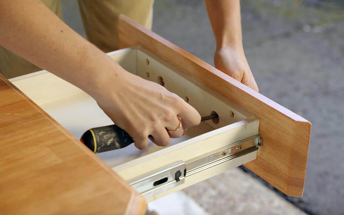 Someone using a screwdriver to remove a drawer's front.