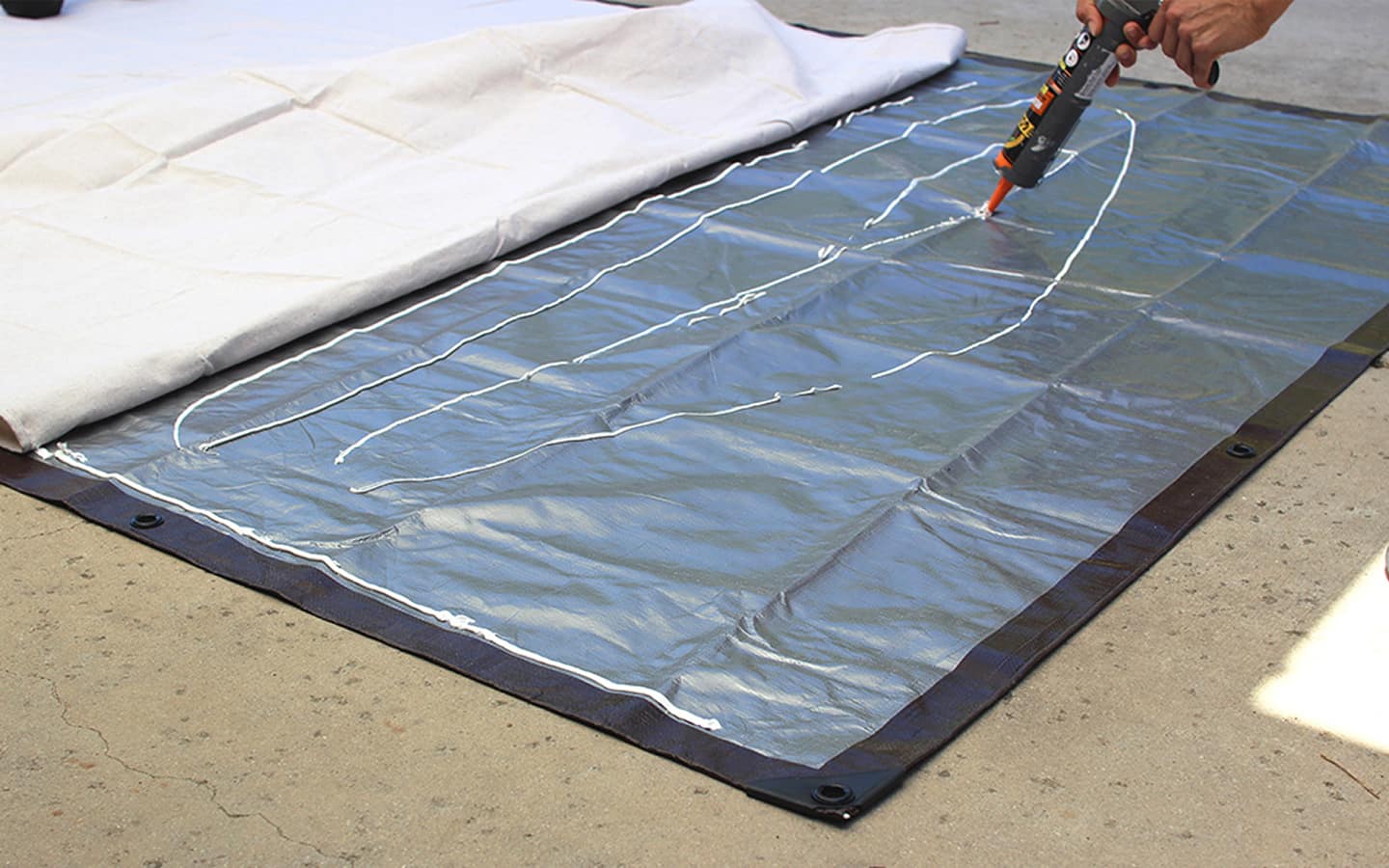 Adhesive is dispensed onto the tarp.