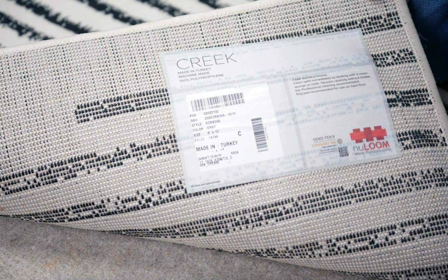 A black- and white-striped rug pulled back to reveal its care label. A black- and white-striped rug pulled back to reveal its care label.
