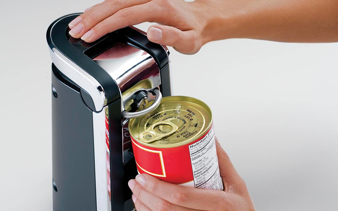 Someone using an electric can opener. Someone using an electric can opener.