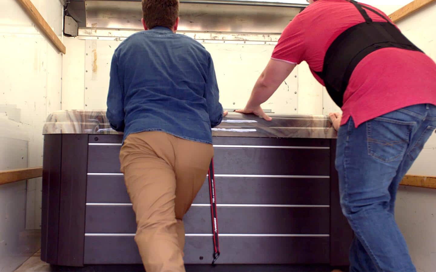 Two men moving a hot tub into a truck.