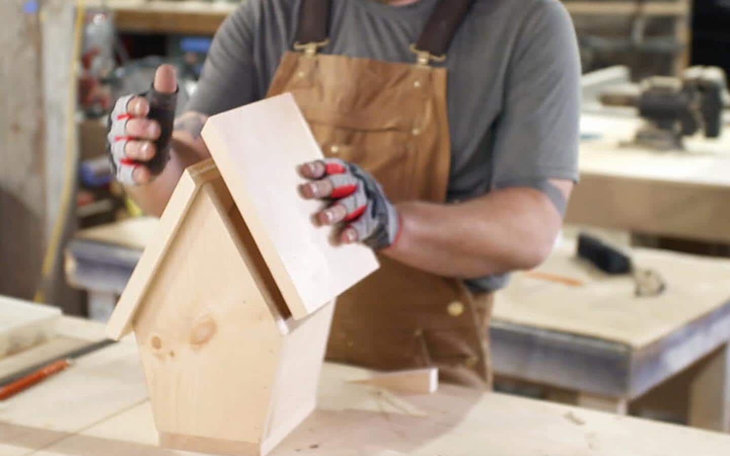 The left panel of a birdhouse's roof being attached to the other boards.