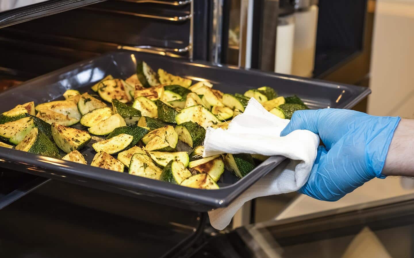 Someone pulling a pan of roasted vegetables from oven. Someone pulling a pan of roasted vegetables from oven.