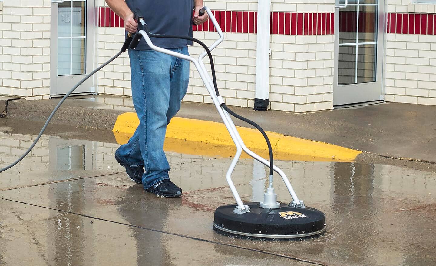 A man cleaning a parking lot with a pressure washer.