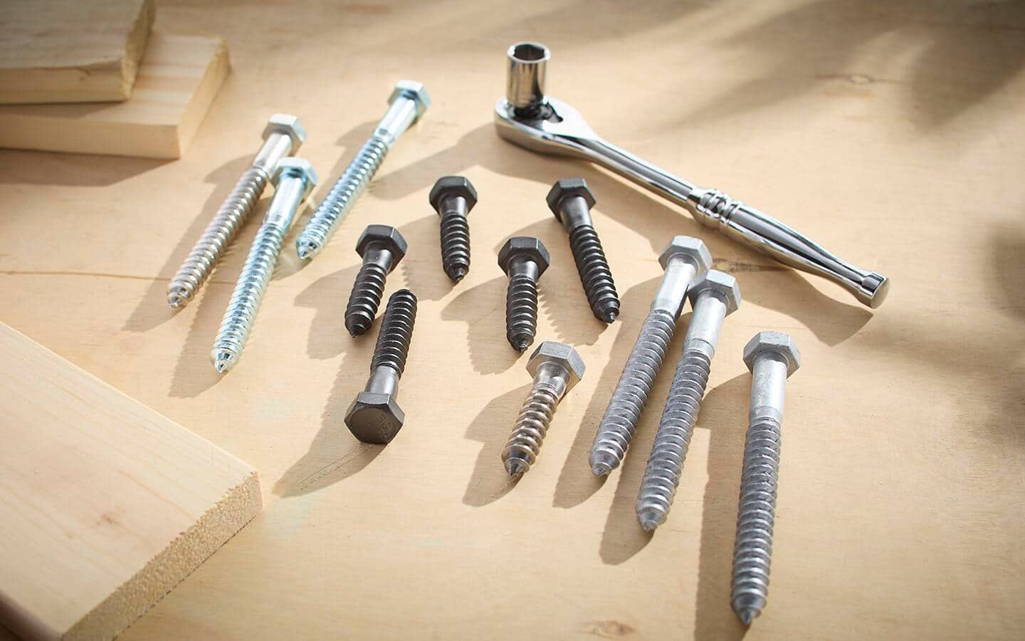 A ratchet wrench and socket with lag bolts in several different finishes.