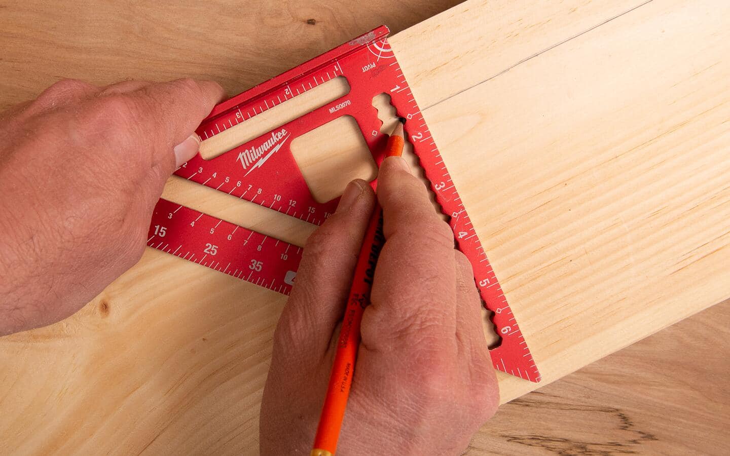 A person using a pencil and square to mark a rip cut. A person using a pencil and square to mark a rip cut.