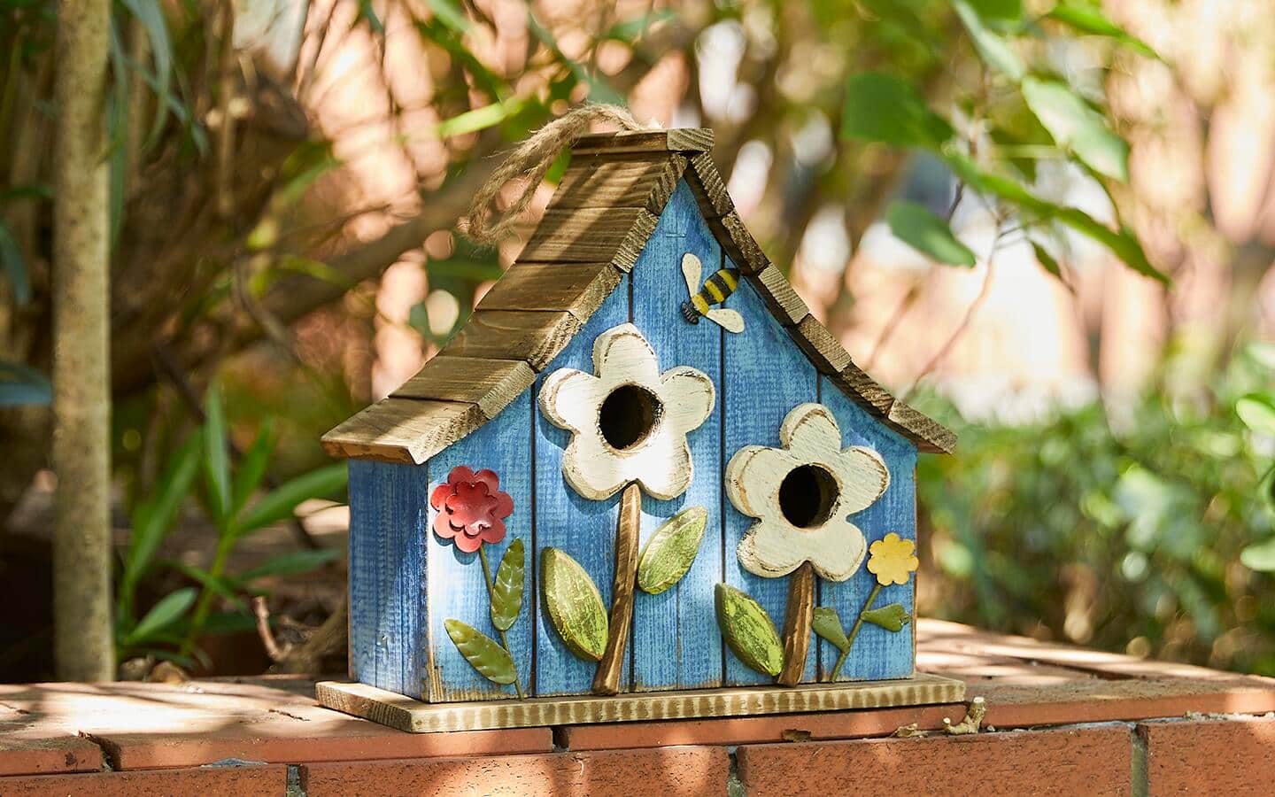 A whimsical birdhouse featuring a folk art theme of large flowers.