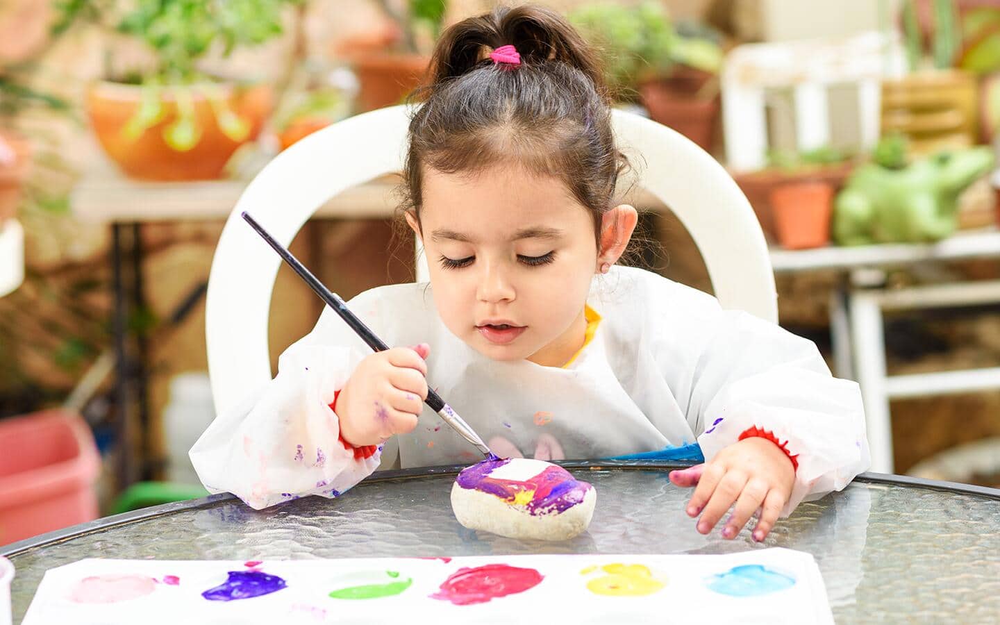 A small child paints rocks to put in a garden A small child paints rocks to put in a garden