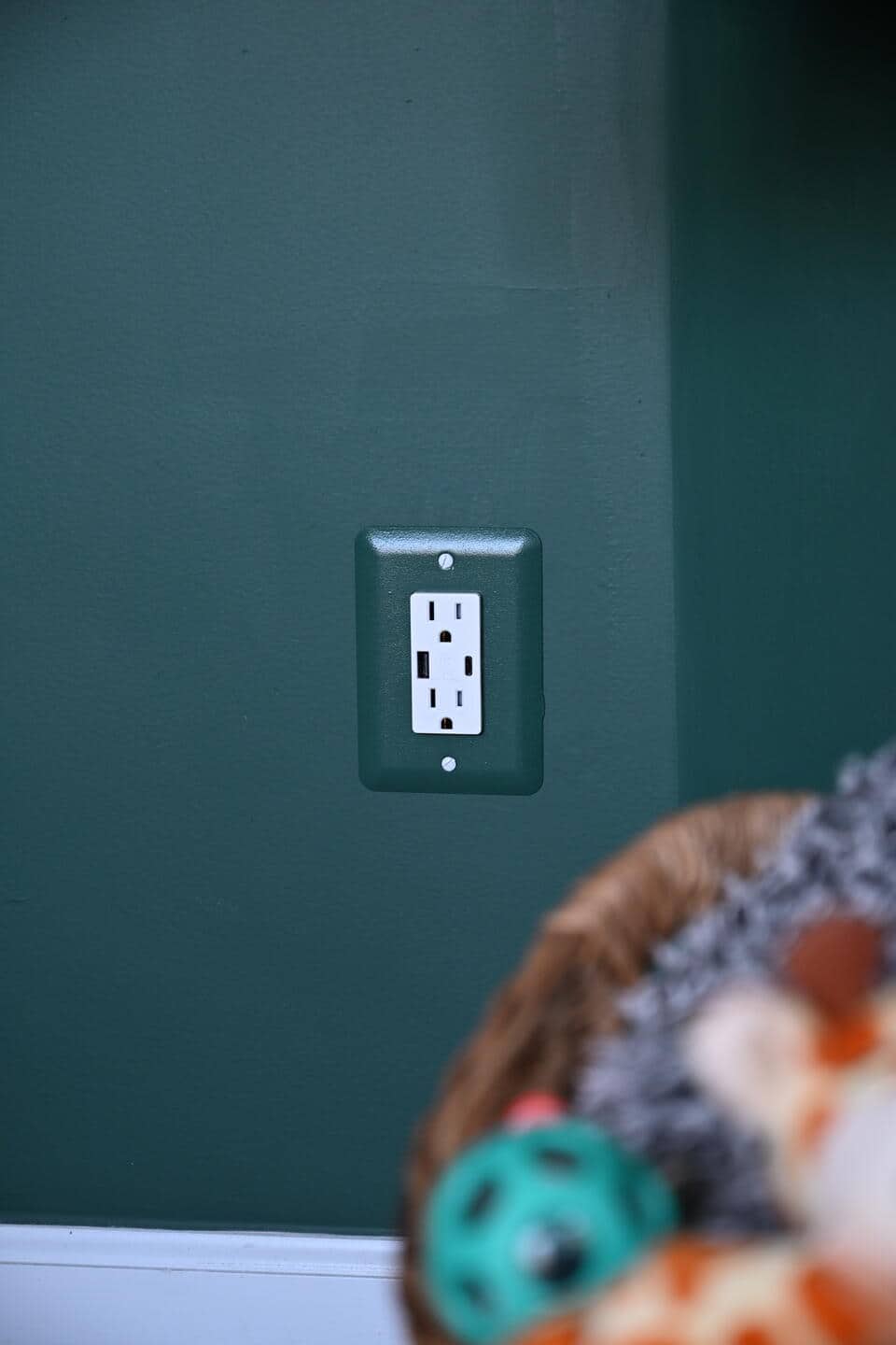 A close-up photo of the green-painted outlets that seamlessly blend into the green walls of the new office. These outlets have special plugs to be able to directly charge devices and appliances that are compatible with USB and lightening cable ports.