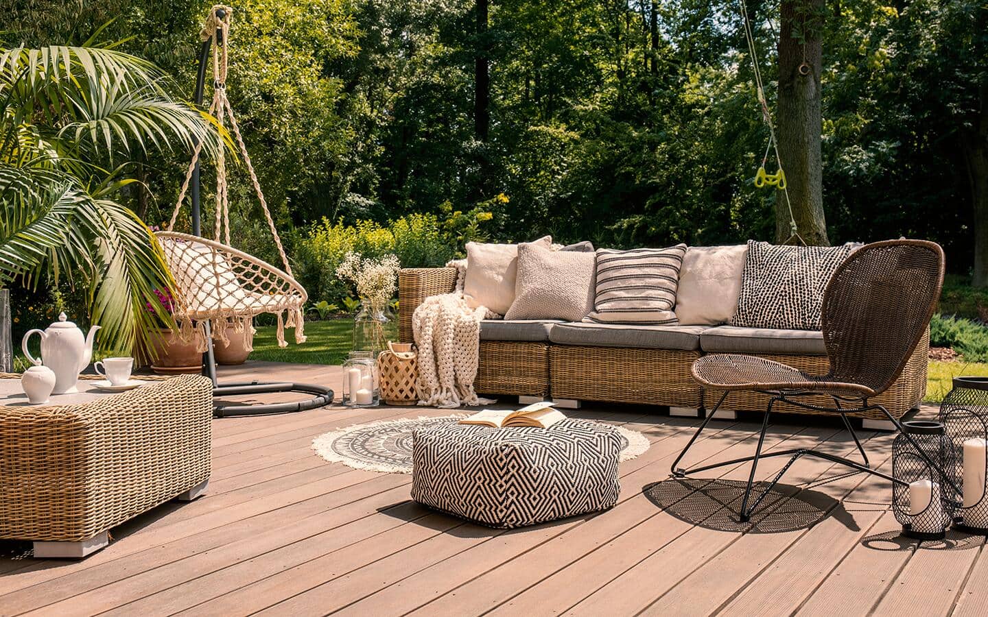 A freestanding deck with an outdoor sofa, ottoman, hanging chair and small rug. A freestanding deck with an outdoor sofa, ottoman, hanging chair and small rug.