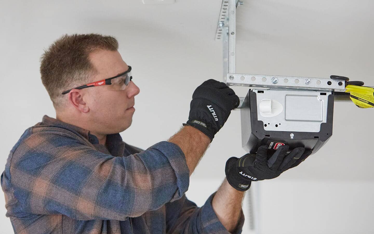 Person installs a smart garage door opener on the ceiling of a garage