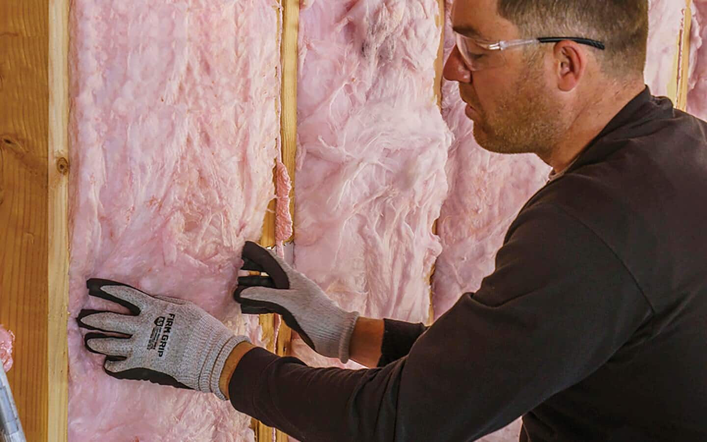 A person installs insulation in a wall.
