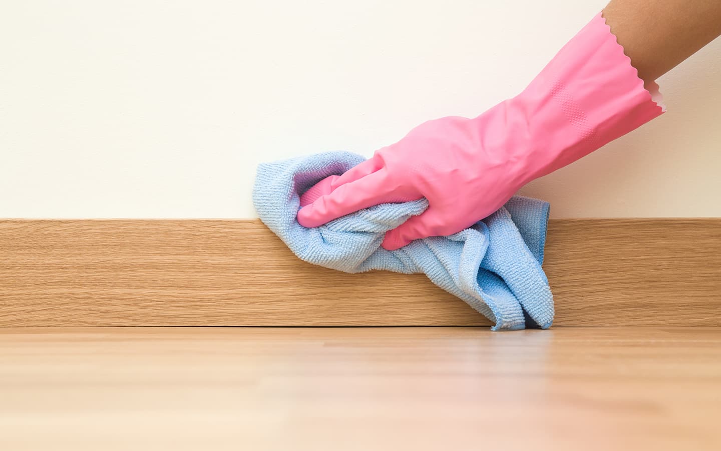 A person wipes a baseboard with a cloth. A person wipes a baseboard with a cloth.