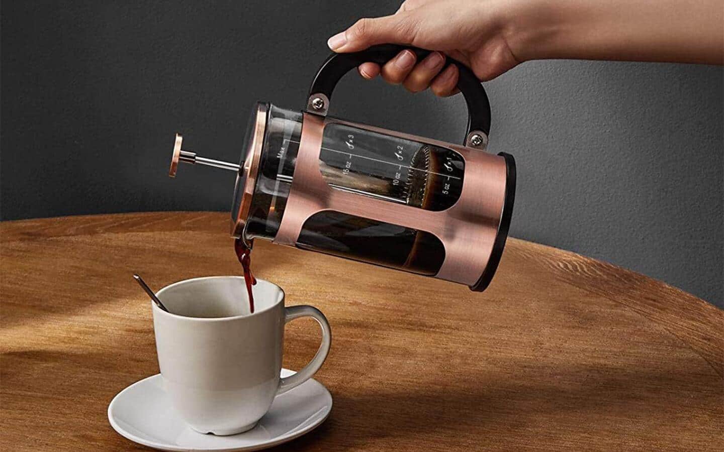 Woman pouring coffee from a French press into a coffee cup