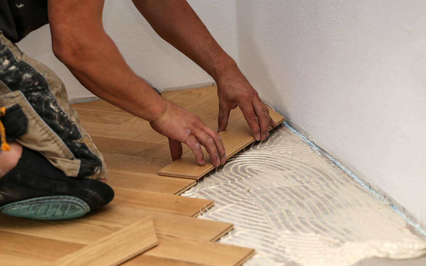A person lays tile into a parquet pattern on a floor. A person lays tile into a parquet pattern on a floor.