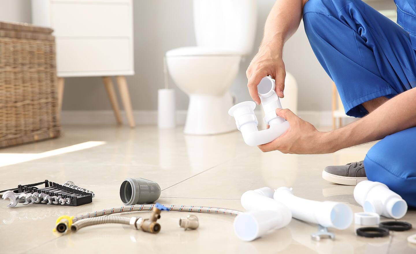 Someone working on plumbing pipes in a bathroom.