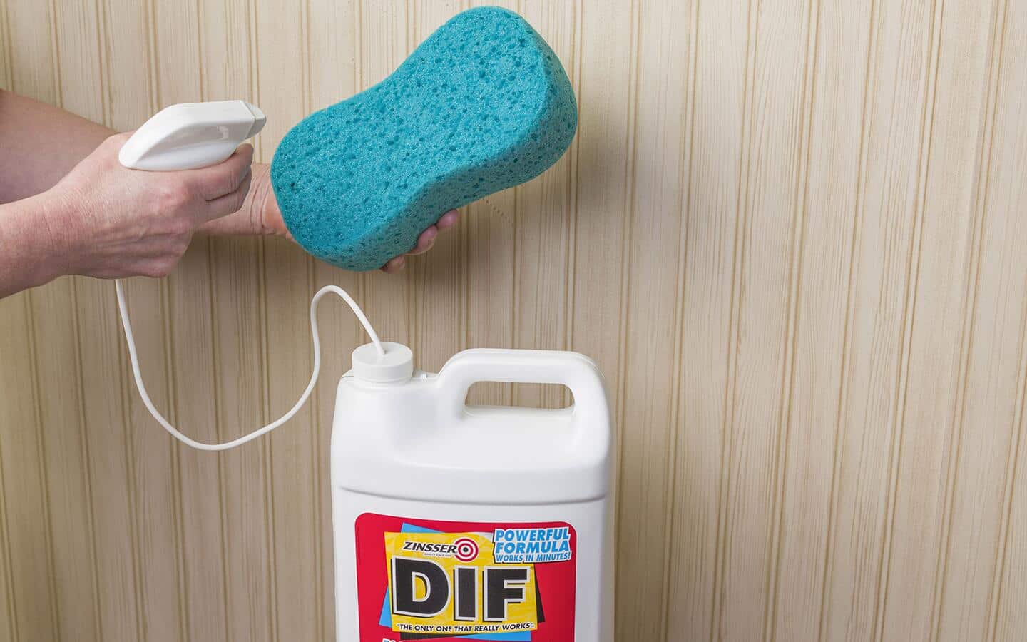 A person sprays wallpaper remover onto a sponge. A person sprays wallpaper remover onto a sponge.