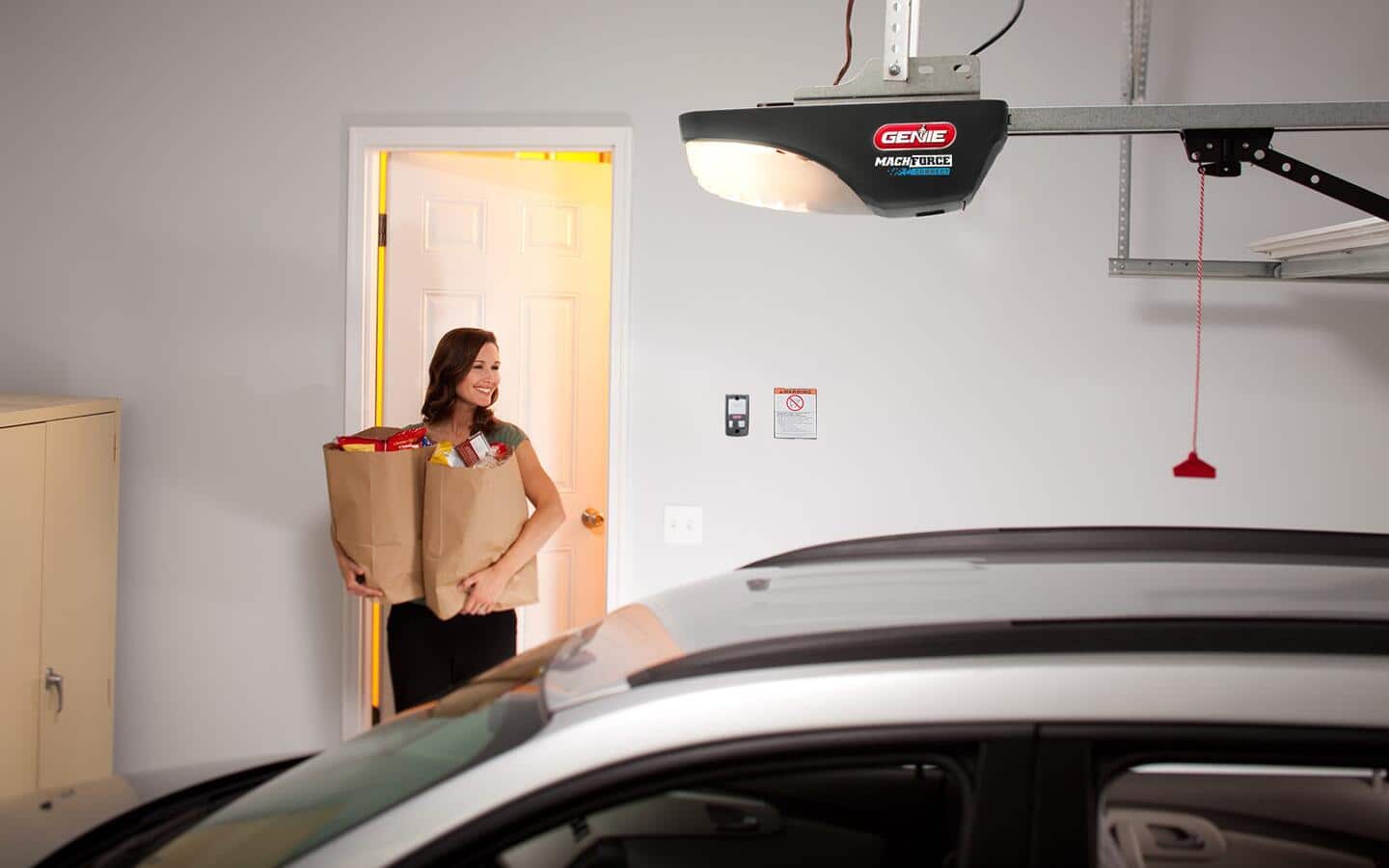A screw drive garage door opener hangs from a ceiling.