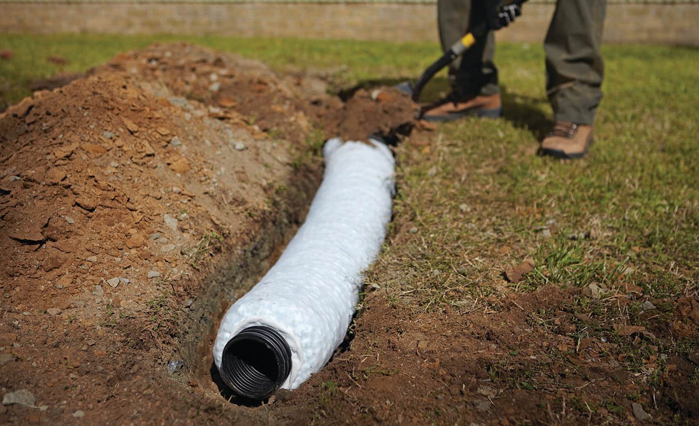 A person installing a gravel-free French drainage system.