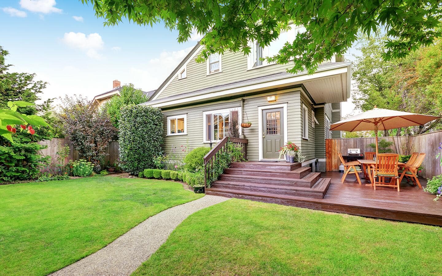 A home's side yard deck includes a grill and an umbrella over a table and chairs. A home's side yard deck includes a grill and an umbrella over a table and chairs.