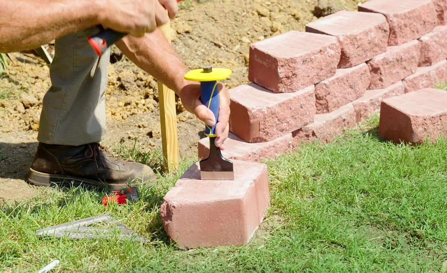 A concrete retaining wall block is scored before it is split.