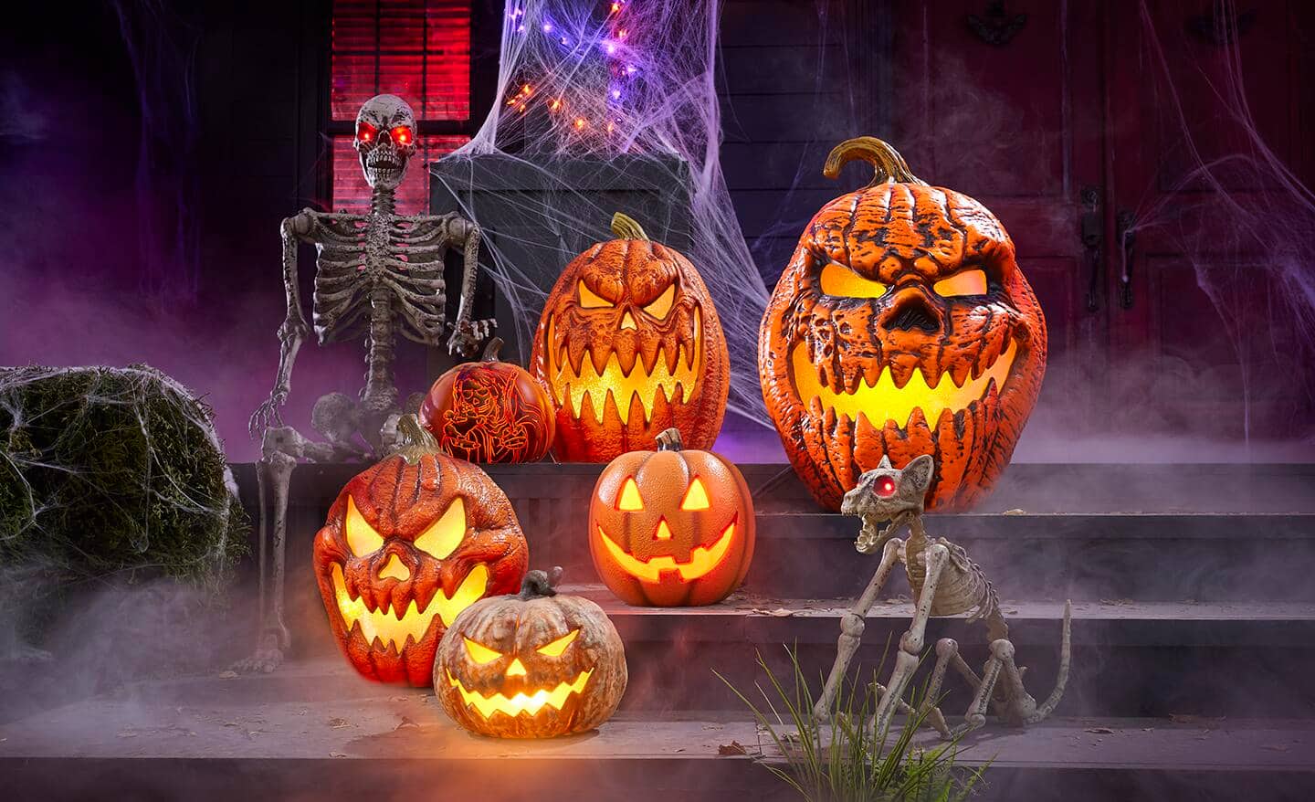 Multiple lit-up Jack-'o'-lanterns sit on a porch decorated for Halloween.
