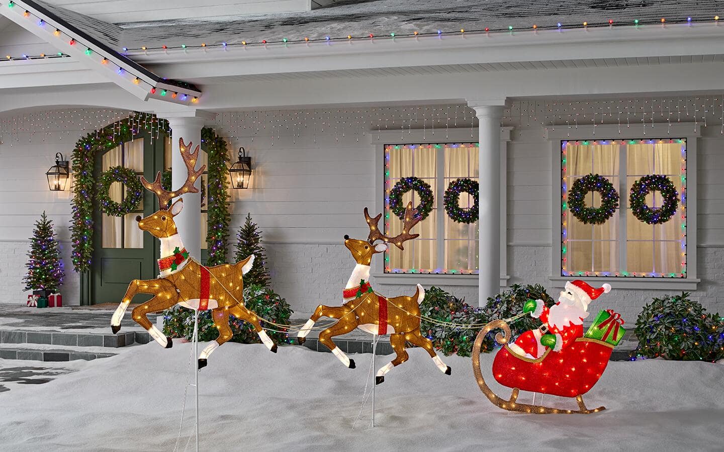 Santa sits in a sleigh while reindeer prepare for liftoff on a lawn in front of a decorated home. Santa sits in a sleigh while reindeer prepare for liftoff on a lawn in front of a decorated home.